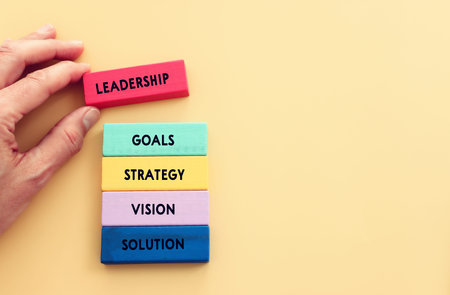 Wooden colorful cubes and the word leadership on paper background.