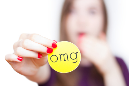 Close-up of girl reacting surprised holding up an omg sign isolated on white with faded background.の写真素材