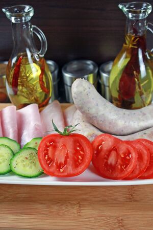 Tomatoes, ham, cucumber and white sausage on a plateの写真素材