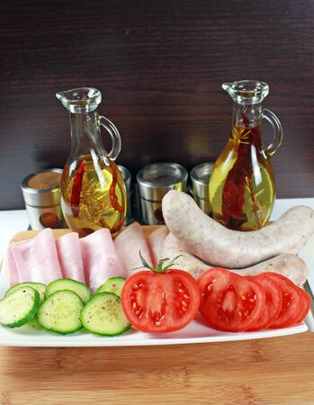 Tomatoes, ham, cucumber and white sausage on a plateの写真素材