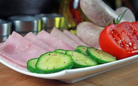 Tomatoes, ham, cucumber and white sausage on a plateの写真素材