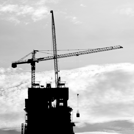 silhouette of Industrial construction cranes and buildingの写真素材