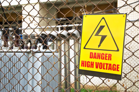 Danger high voltage warning sign on a fence in transformer station の写真素材
