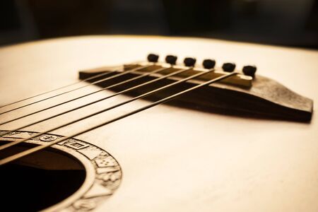 detail of acoustic guitar focus on bridge and strings, very shallow depth of field