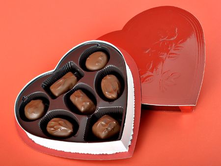Heart shaped box of candies on red background