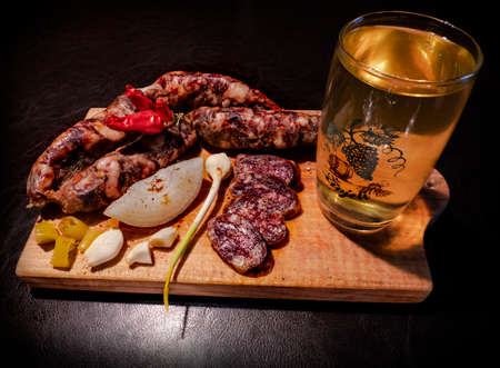 Smoked homemade meat sausage with white wine served on the wooden cutting board with vegetablesの写真素材