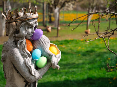 Stone lady statue with rusty crown holding colorful Easter eggs