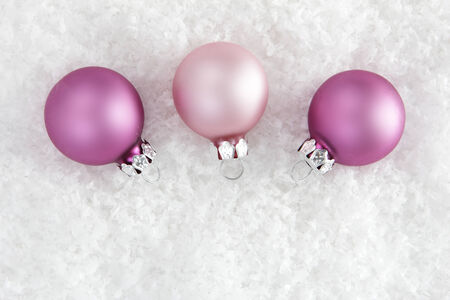 pink christmas balls on artificial snow with white backgroundの写真素材