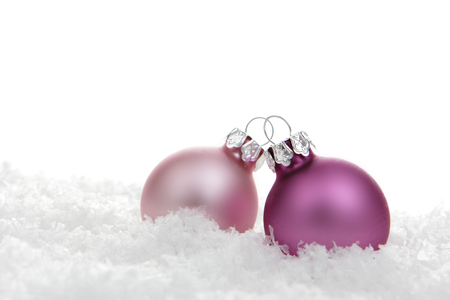 pink christmas balls on artificial snow with white backgroundの写真素材