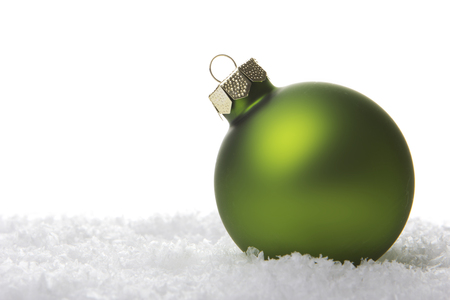 green christmas baubel on artificial snow with white backgroundの写真素材
