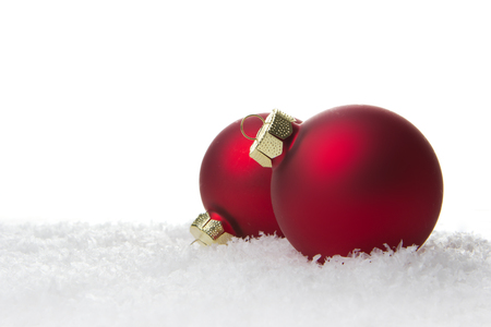 red christmas balls on artificial snow with white backgroundの写真素材