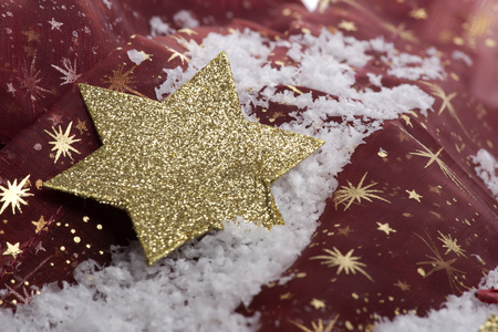 golden christmas star on artificial snow with decorationの写真素材