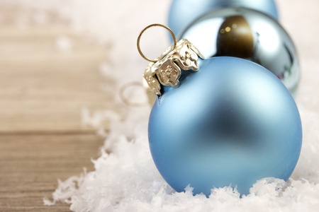 christmas decoration with wooden background, snow, christmas baubles blue and silver の写真素材