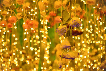Flower garland in the shape of a heart on a background of yellow lightsの写真素材