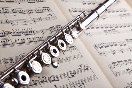 Silver flute on an ancient music score backgroundの写真素材
