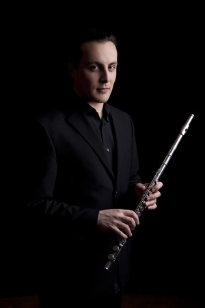 professional flutist musician playing flute on black backgroundの写真素材