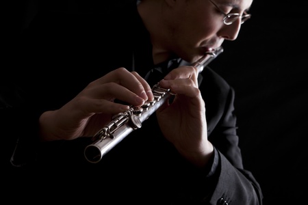 professional flutist musician playing flute on black backgroundの写真素材