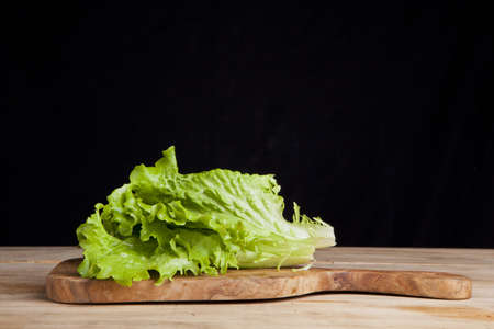 lettuce leaf on cutting board on black backgroundの写真素材