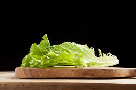 lettuce leaf on cutting board on black backgroundの写真素材