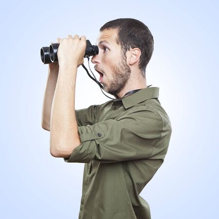 young man looking through binoculars, surprise face expressionの写真素材
