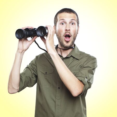 young man looking through binoculars, surprise face expressionの写真素材