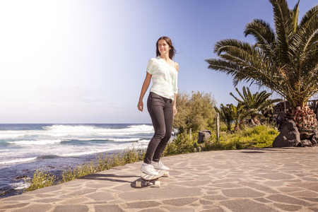 beautiful young skater woman with a longboard near the seaの写真素材
