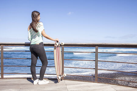 beautiful young skater woman with a longboard near the seaの写真素材