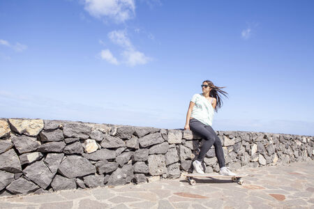 beautiful young skater woman with a longboard near the seaの写真素材