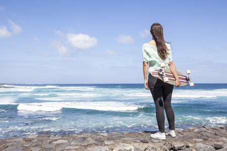 beautiful young skater woman with a longboard near the seaの写真素材