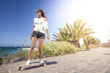 beautiful young skater woman with a longboard near the sea