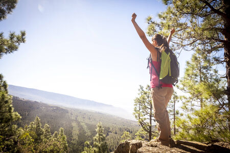 young woman on top of the moutain with the arms raised enjoying freedom.の写真素材