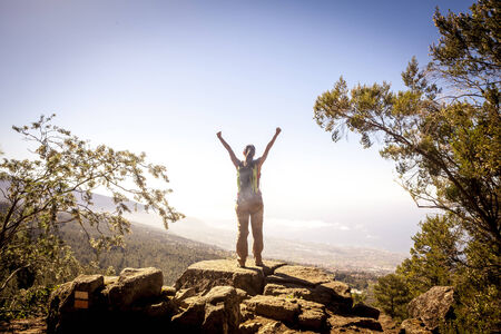 young woman on top of the moutain with the arms raised enjoying freedom.の写真素材