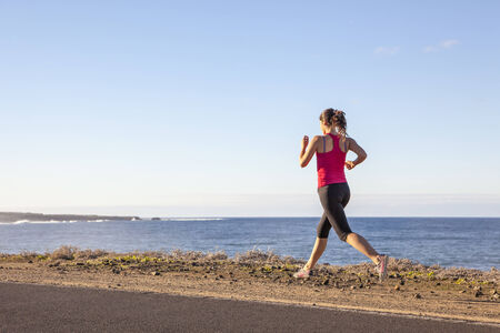 atlhlete woman running near the sea. Healthy active lifestyle young woman exercising outdoors.の写真素材