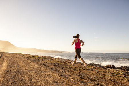 atlhlete woman running near the sea. Healthy active lifestyle young woman exercising outdoors.の写真素材