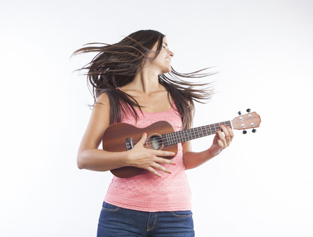 young beautiful brunette woman playing ukulele and having funの写真素材