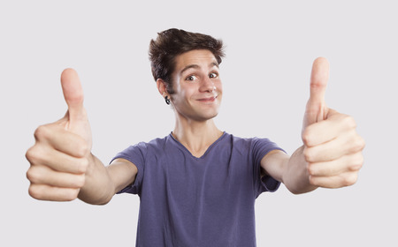 happy young man with thums up, funny face expressionの写真素材