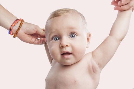 portrait of a cute blue eyes newborn baby holding his mother's hands