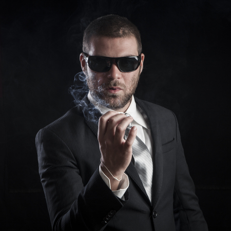 portrait of a tough cool man with sunglasses on balck backgroundの写真素材