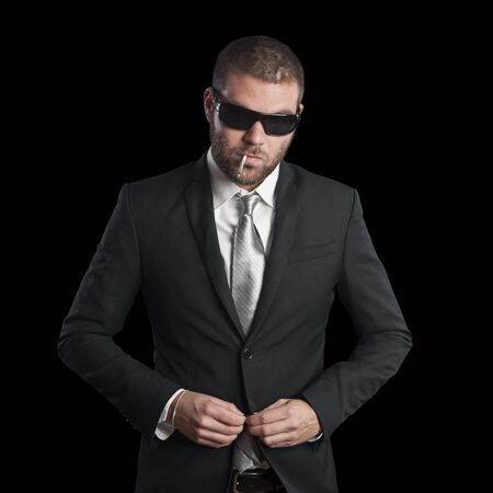 portrait of a tough cool man with sunglasses on balck backgroundの写真素材