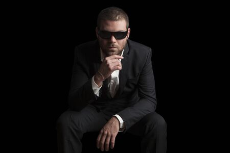 portrait of a tough cool man with sunglasses on balck backgroundの写真素材