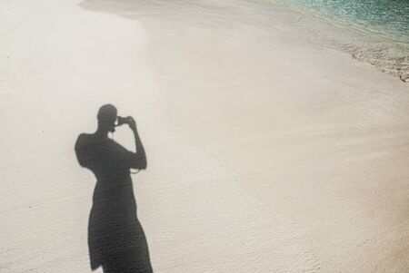man's shadow on a tropical beachの写真素材