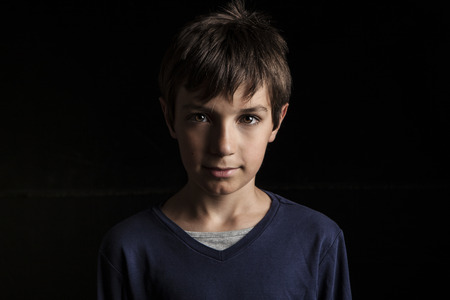 Portrait of adorable young happy boy on dark backgroundの写真素材