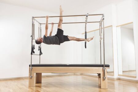 Pilates instructor performing fitness exercise on cadillac equipment, at the gym indoorの写真素材