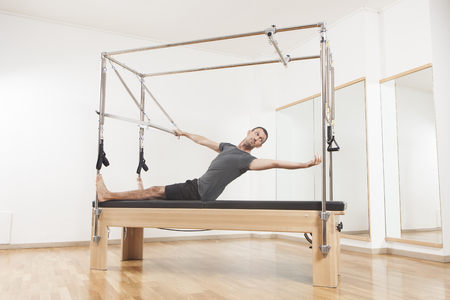 Pilates instructor performing fitness exercise on cadillac equipment, at the gym indoorの写真素材