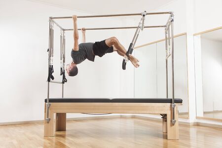 Pilates instructor performing fitness exercise on cadillac equipment, at the gym indoor