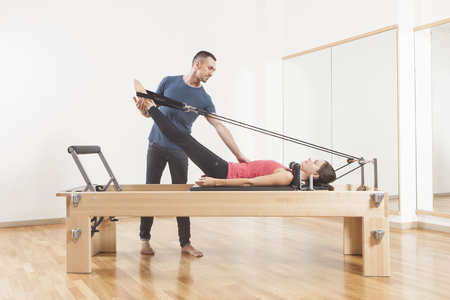 Pilates lesson on reformer, personal coaching young beautiful womanの写真素材