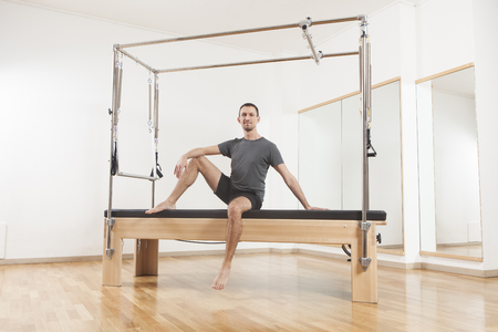 Pilates instructor performing fitness exercise on cadillac equipment, at the gym indoorの写真素材