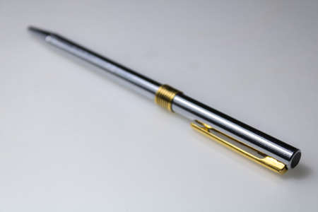 metal pen, with golden and silver colors, in a transversal position, on a white surfaceの写真素材