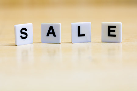 A row of small white plastic tiles, containing the letters forming the word sale, to represent the concept of discount.の写真素材