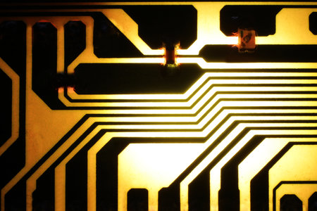The backlit photo of a yellow and black electrical circuit, with the black connections directed to the center of the circuit.の写真素材